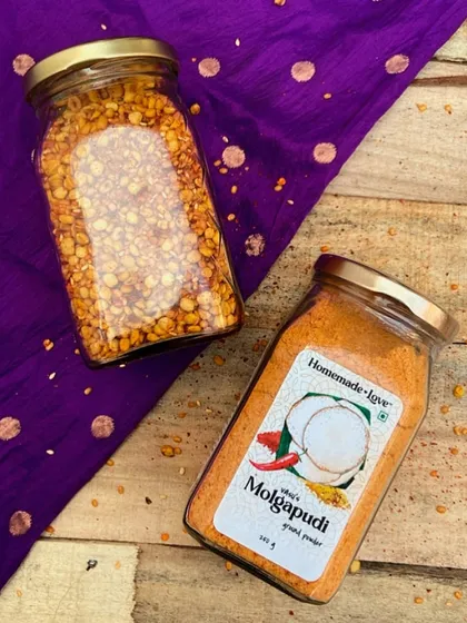 A beautiful shot showing the key ingredients and the final product. You can see the dals and chilies in one jar and the ground Molgapudi powder in another, illustrating our transparent, from-scratch process.