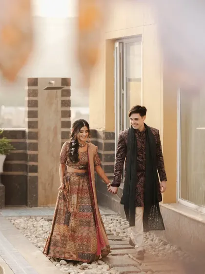 The couple walks hand-in-hand during their Sangeet event. This candid shot captures a simple, happy moment between them.