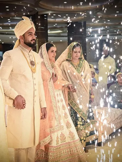 The grand entrance of the bride and groom, surrounded by family and sparkling lights. This photo captures the celebratory atmosphere of a Muslim wedding reception.