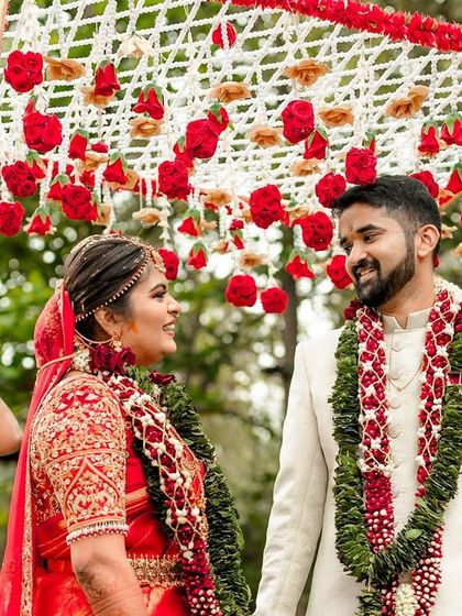 The bride and groom sharing a look under a canopy of red roses. This shot captures the anticipation and excitement of the wedding procession.