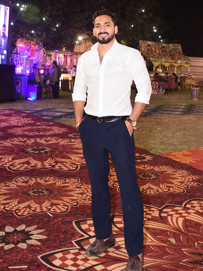 A happy client looking sharp and elegant at an event in a custom-designed white shirt. The piece features intricate, tone-on-tone embroidery for a touch of subtle luxury.