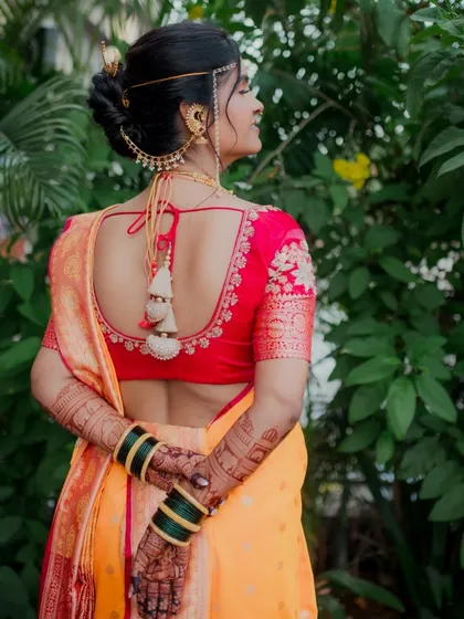 This portrait focuses on the stunning details of the bride's attire from behind. It showcases her elegant blouse design, traditional hairstyle with ambada pin, and the rich patterns of her mehndi.