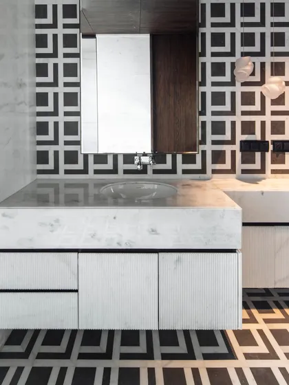 The master washroom in our Kolkata project, featuring bold black and white geometric marble tiles. A floating fluted marble vanity and custom wall lights create a glamorous, Art Deco-inspired feel.
