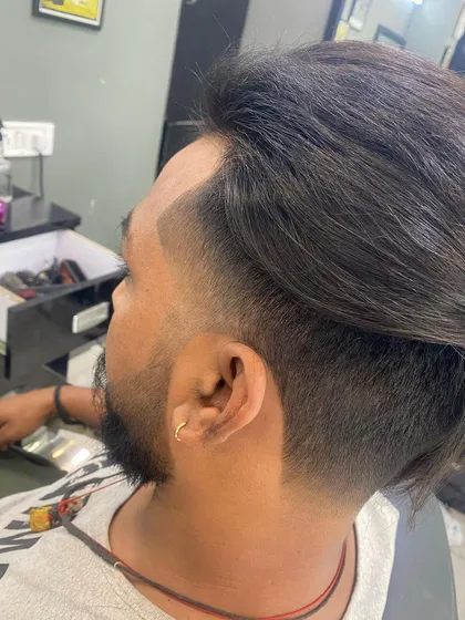 For clients who prefer longer hair on top, a sharp fade on the sides provides a great contrast. This look combines a classic swept-back style with a modern, faded beard connection.