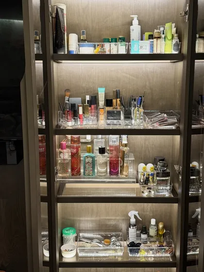 A full view of a beautifully organized beauty cabinet. With tiered shelves and clear trays, every product from skincare to fragrance has its own place, creating a functional and aesthetically pleasing display.