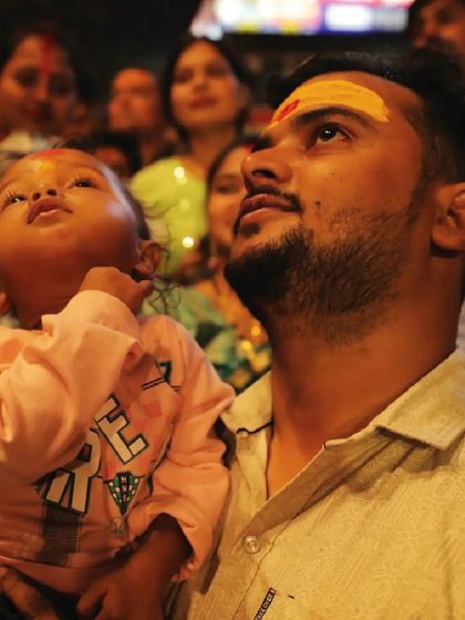 A father holds his child up to see the drone show in Varanasi. Our shows are for all ages, creating memories that families can share for a lifetime.