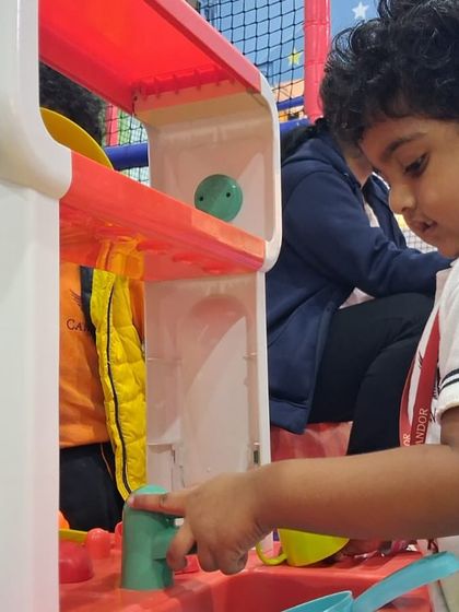 Our junior chef activities let kids explore the world of cooking. This little one is completely absorbed in pretend play at a toy kitchen station, learning about food and developing life skills.