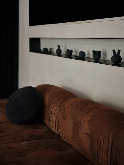 A small, curated collection of black ceramic objects sits in a niche above the living room sofa. These subtle details add personality and an artistic touch to the space.