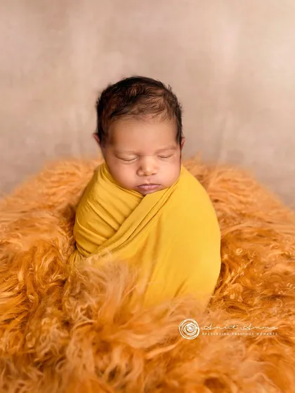A simple and sweet portrait. The baby, wrapped in yellow, is the bright center of this cozy and warm composition.
