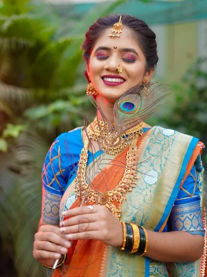 This portrait captures a moment of serene bliss. With her eyes closed and a gentle smile, the bride looks completely at peace. The peacock feather adds a soft, delicate touch to this beautiful bridal shot.