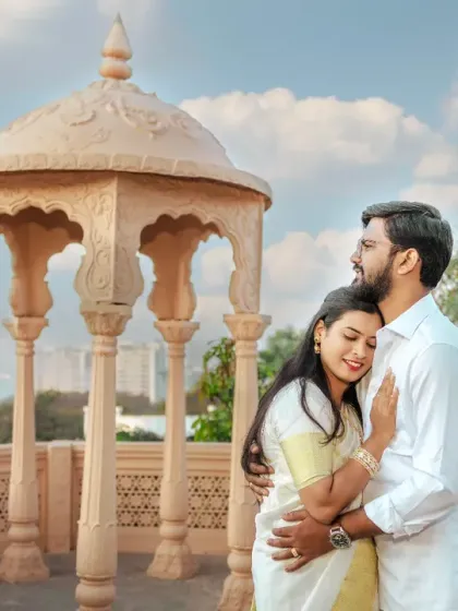 This tender moment was captured during a pre-wedding shoot with a South Indian theme. The soft morning light and the couple's gentle embrace against the classic architecture create a feeling of timeless romance.