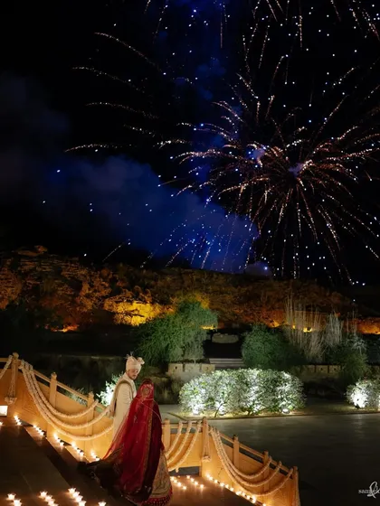 Priyangi and Kishan walk down to their reception at Suryagarh, Jaisalmer, as fireworks light up the night sky. The grandeur of the palace and the celebration is truly breathtaking.