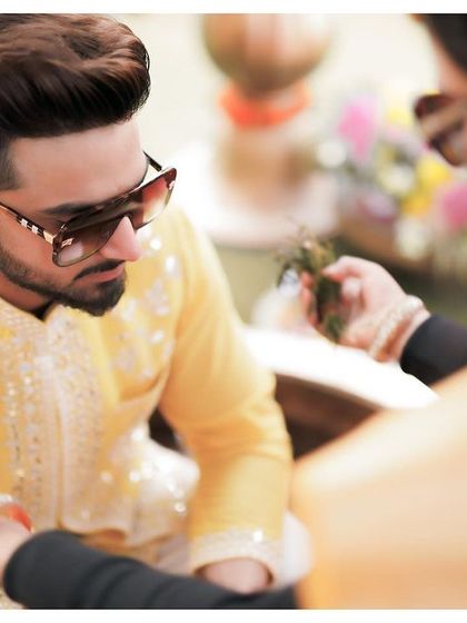 A detail shot of a guest applying a tikka to the groom, capturing the small, significant rituals of the Haldi ceremony.
