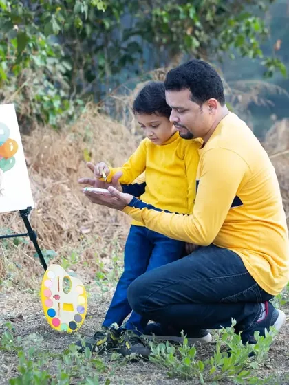 A father helps his son with a painting project during an outdoor family session.