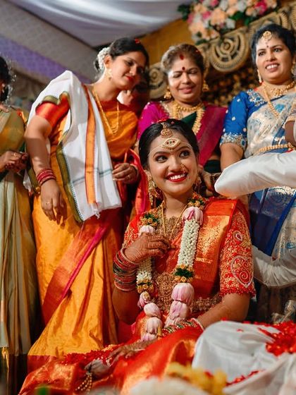 A wide shot of a wedding ritual, showing the bride surrounded by her smiling family and friends.