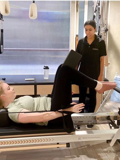 One-on-one instruction helps you connect with your core muscles on a deeper level. Here, our trainer guides a client through a leg press on the reformer, ensuring proper engagement for improved stability.