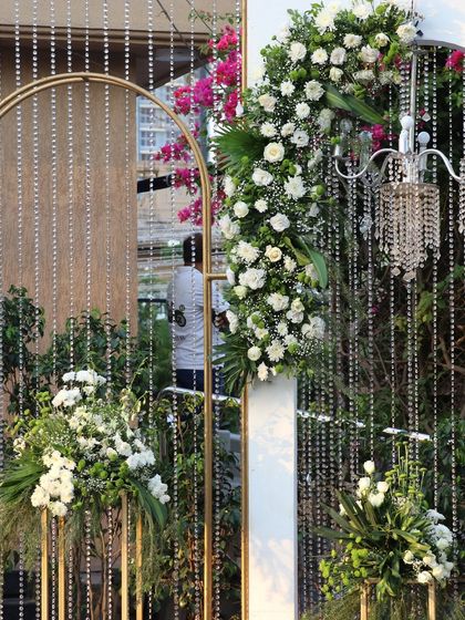 A stunning detail of a floral arch with hanging crystal strings, blending natural beauty with glamorous sparkle.