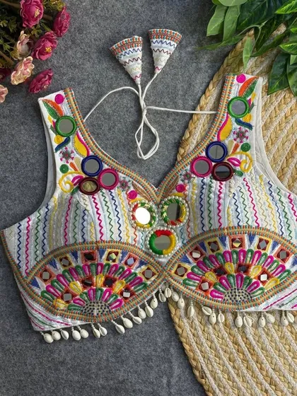 This is one of my favorite statement blouses. The combination of multi-color threadwork, mirror embellishments, and cowrie shell details makes it a standout piece you can pair with many different skirts.