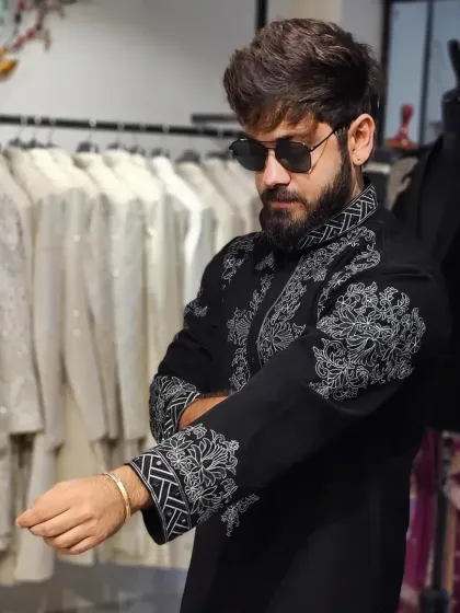 A client trying on a black kurta with bold, white threadwork embroidery. The design is modern and graphic, perfect for a stylish man.