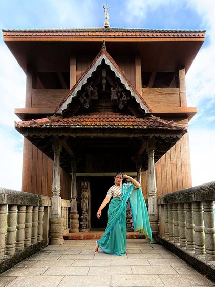 A full-length shot showcasing a graceful dance pose in front of a stunning heritage building in Kerala. This photo is a celebration of Indian heritage and art.