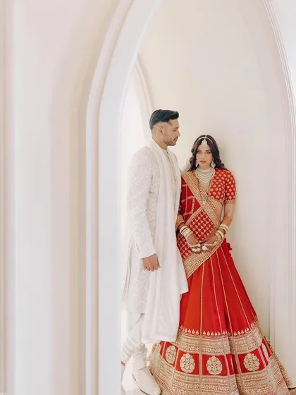A full-length shot of the couple, Arjun Kanungo and Carla Dennis. I worked to ensure their outfits were perfectly coordinated, with Arjun in a classic white sherwani complementing Carla's red lehenga.