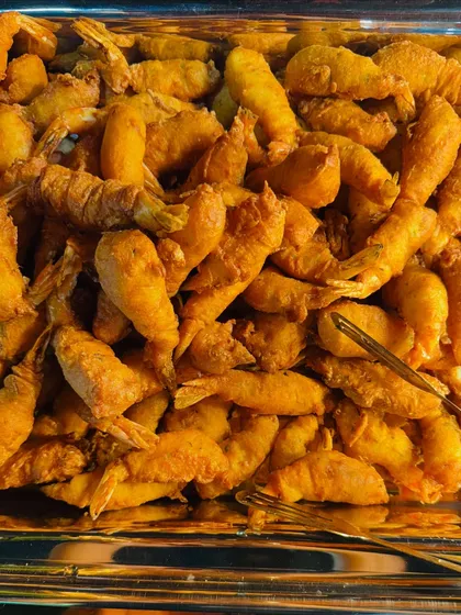 A close-up of the perfectly crispy and delicious golden fried prawns, a classic party appetizer.