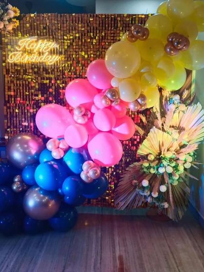 A unique balloon backdrop with a gold sequin wall and a colorful mix of blue, pink, and yellow balloons.