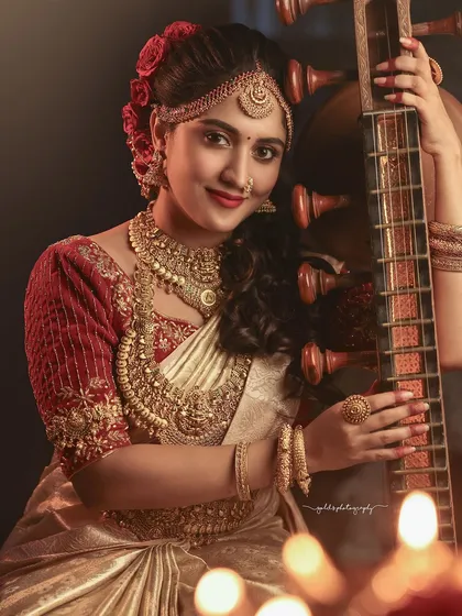 A portrait that combines music and tradition. The bride's joyful expression as she holds the veena, surrounded by the soft glow of diyas, creates a warm and festive atmosphere.