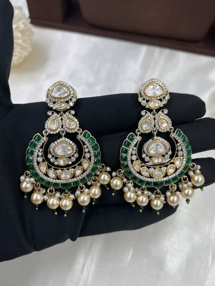 One of our most requested bridal sets, this design features large uncut Kundan stones, green Meenakari work, and pearl detailing. The set includes a necklace, chandbali earrings, and a matching maang tikka.