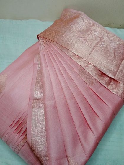 This pastel pink saree has a subtle elegance, enhanced by the perfectly formed pleats. It's ready for any daytime event or formal gathering.