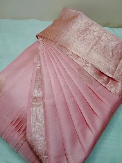 A soft, elegant pink silk saree with a subtle gold border.
