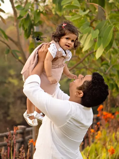 A father lifts his daughter up, both of them smiling. These playful, interactive shots result in the most natural and heartwarming family photos.