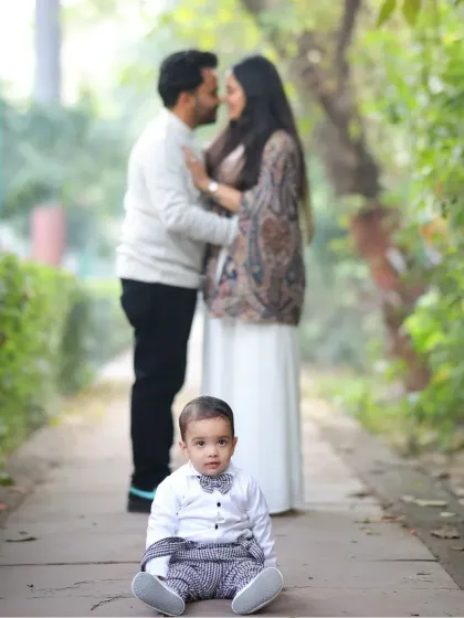 A beautiful family portrait with the baby in focus. The soft, natural background of the park creates a lovely, gentle mood for the photo.