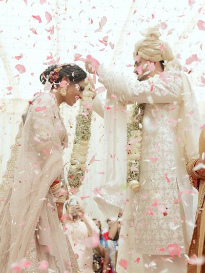 A shower of petals during the varmala ceremony. This photo captures the peak of the ritual, with the couple surrounded by flowers, creating a magical and memorable portrait.