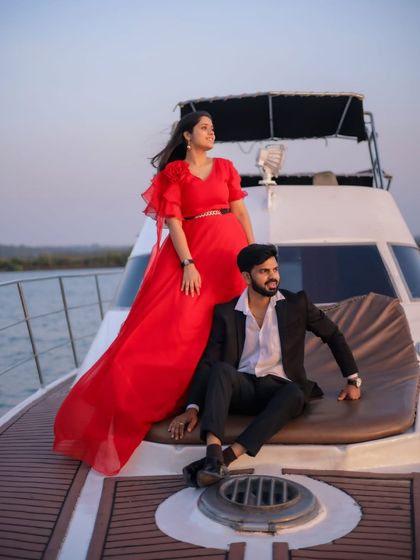 A luxurious pre-wedding shoot on a yacht. The bright red gown with flutter sleeves is a glamorous choice for a statement-making photo on the water.