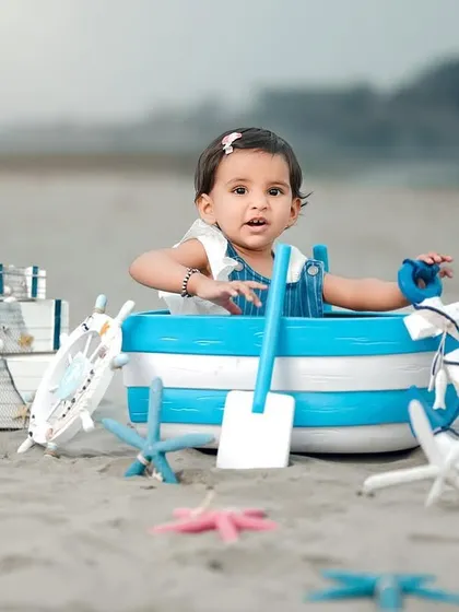 A beautiful portrait of a little girl in a nautical-themed beach shoot. The soft sand and gentle waves create a serene and lovely backdrop.