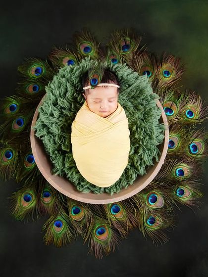 A creative Krishna-themed newborn shoot, with the baby nestled in a bed of peacock feathers. A unique way to celebrate your new arrival.