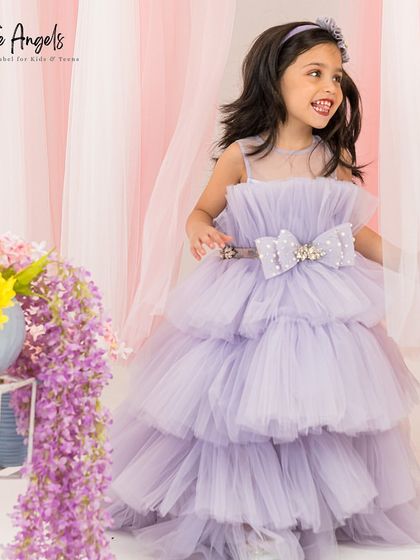 A smiling girl in our lilac high low gown, perfect for showing off a pair of sparkly shoes.