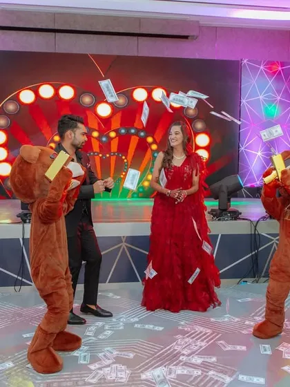 The couple on stage with money-shooting mascots, perfectly capturing the fun and quirky 'Toy Room' theme of their cocktail event. Every detail is planned to enhance the chosen theme.