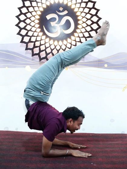A smiling student holds a challenging scorpion forearm stand, radiating joy and accomplishment.