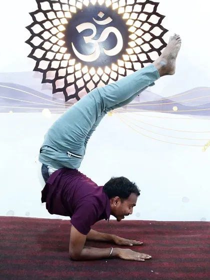 A smiling student holds a challenging scorpion forearm stand, radiating joy and accomplishment.