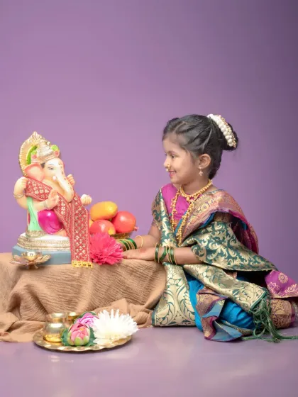 A candid moment where the young girl gazes lovingly at the Ganpati idol. This photo captures the pure and devotional aspect of the festival through a child's eyes.