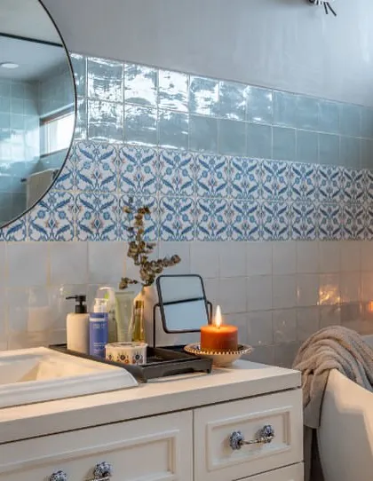 Candles and soft lighting turn this bathroom in Dhaka into a tranquil escape. The combination of patterned and textured blue tiles creates a soothing, water-like effect, perfect for unwinding in the freestanding tub.