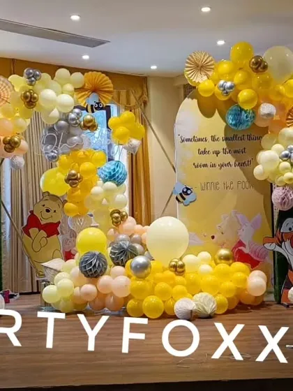 A full view of the Winnie the Pooh themed baby shower, showing the character cutouts and extensive yellow balloon decorations.