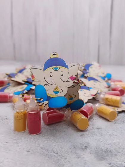 A cute Haldi Kumkum Ganesh set, where a small Ganesha cutout holds tiny bottles of haldi and kumkum. A very creative return gift.