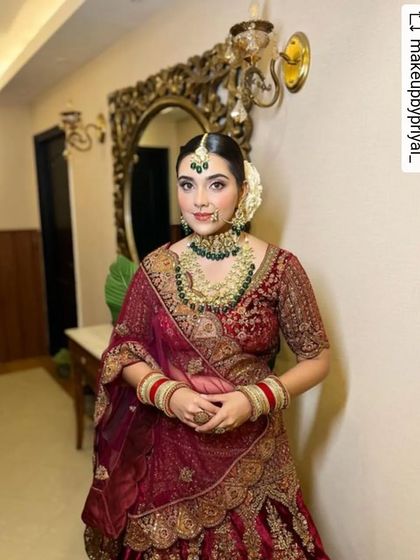 A full view of a minimal bridal look. The deep maroon lehenga is perfectly balanced with soft, natural makeup, creating a look that is sophisticated, modern, and effortlessly beautiful.