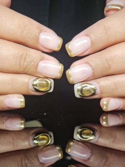 A modern French manicure with a twist, featuring gold chrome tips and a 3D gold accent.