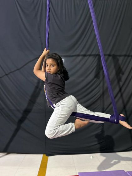 This young student strikes a confident pose in the aerial hammock, demonstrating balance and poise.