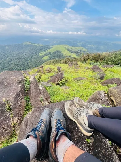 Two pairs of trekking shoes rest on a rock overlooking a beautiful valley. A simple, powerful image of partnership and shared adventure.
