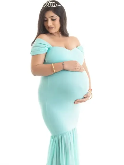 A classic solo maternity portrait in a form-fitting aqua gown with a small tiara. This close-up against a white background highlights the beautiful silhouette of pregnancy.